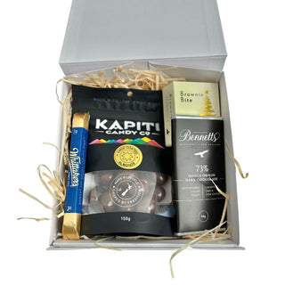 Gift Box Image Small white deluxe gift box with chocolate covered almonds, Bennett's of Mangawhai chocolate bar 60 grams, Whittaker's dark chocolate bar 25 grams and Chocolate Fudge Brownie Bite, shot from above. Batenburgs Gift Baskets Auckland
