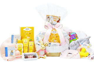 Gift basket featuring baby products such as Weleda body lotion, shampoo and body wash and nappy change cream, Flopsy Rabbit soft toy, rubber duckie, baby blankets, two Peter Rabbit books and house of Chocolate three pack of bon bons