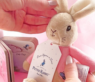 New baby girl gift with a soft Flopsy Bunny rattle and story book from The Tales of Peter Rabbit presented in a white gift box. Delivered NZ wide by Batenburgs Gift Hampers.