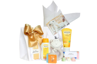 White gift bag with Weleda shampoo and body wash, Weleda Body lotion, peter rabbit book and House of Chocolate three pack bonbons